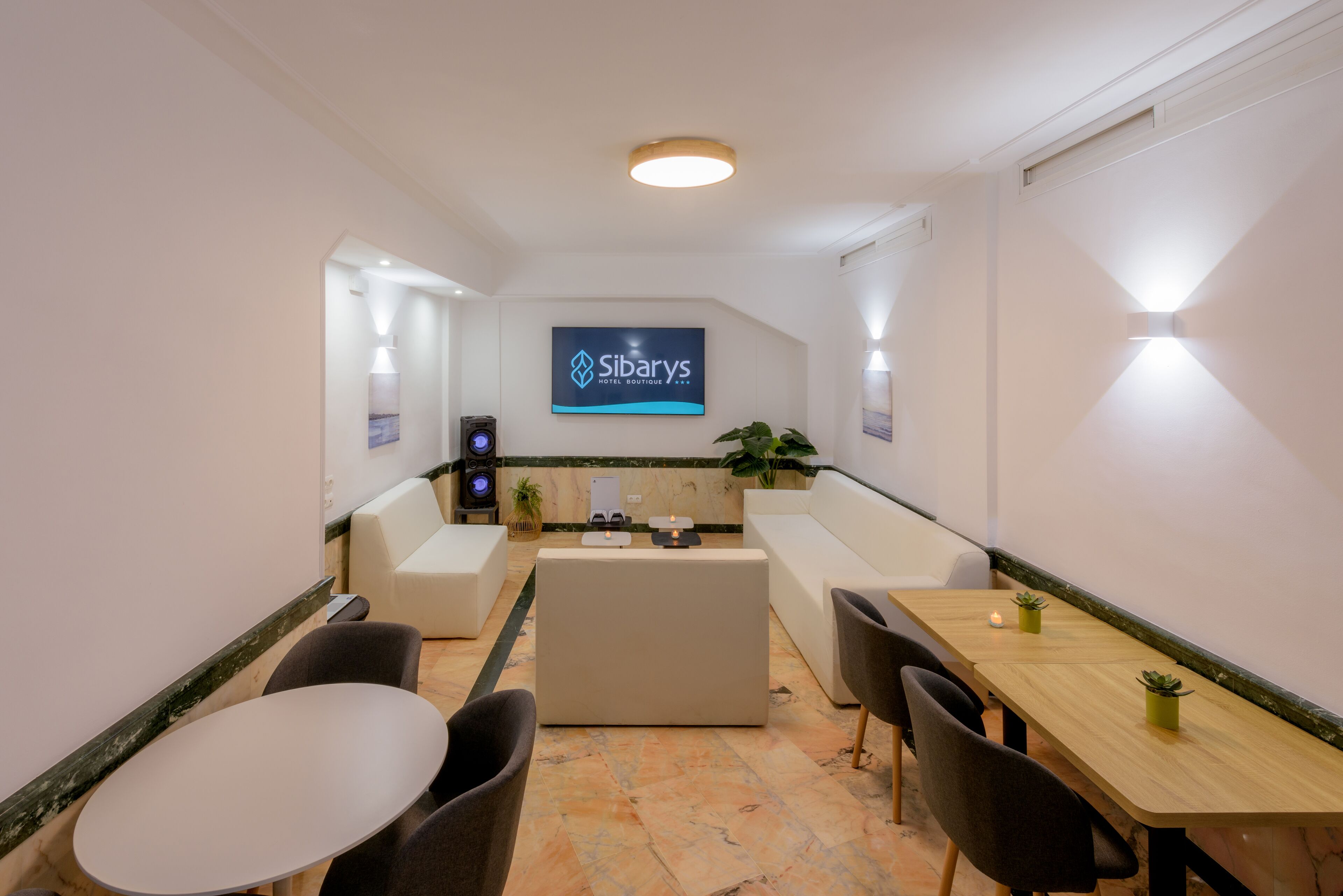 A modern hotel lobby with a large screen displaying the hotel name, comfortable seating areas, and a reception desk.