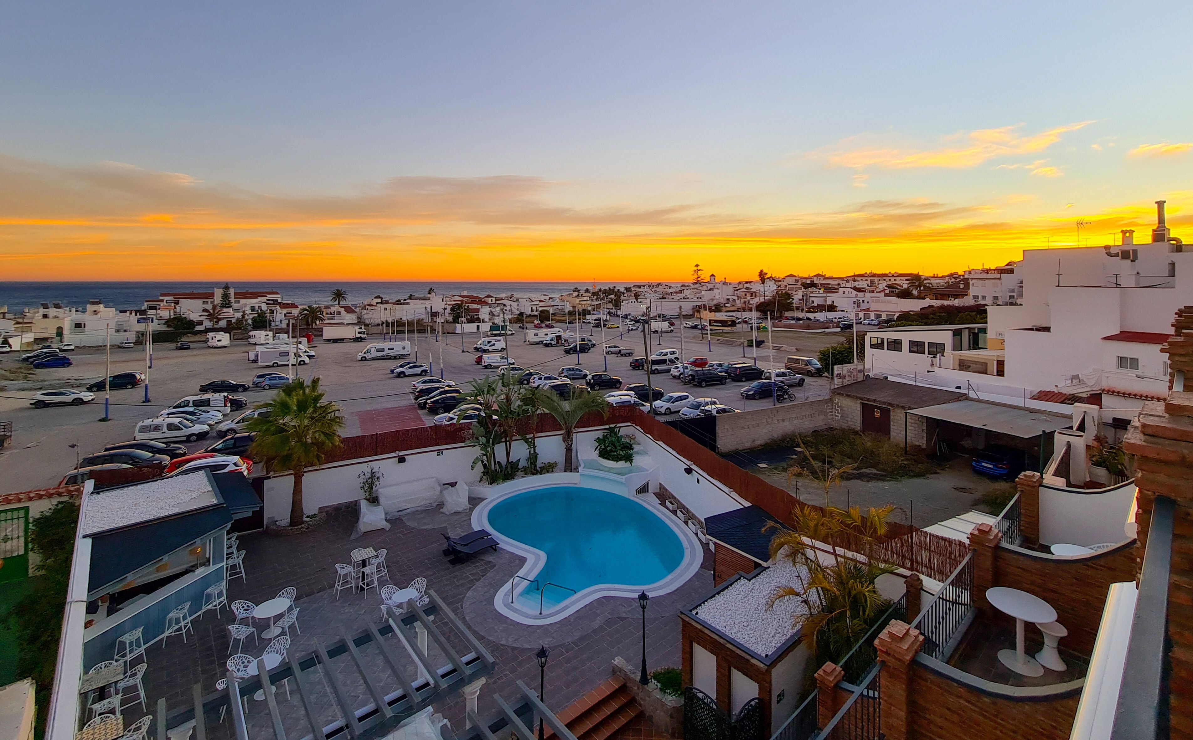 A rooftop pool with a view of a parking lot and buildings in the background.