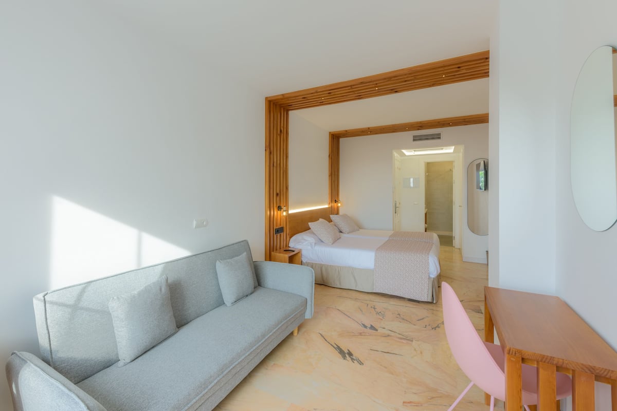 Une chambre d’hôtel moderne avec un canapé, un lit, une table en bois et une chaise.