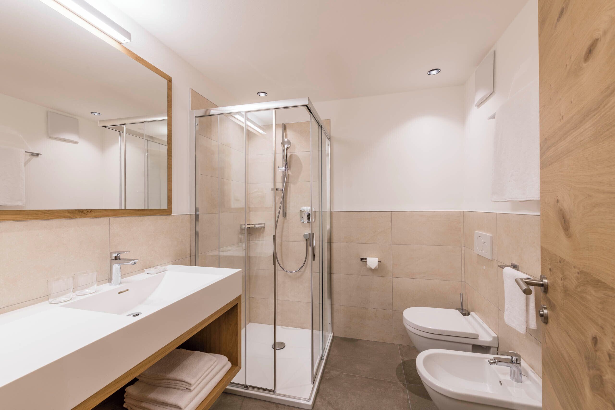 Une salle de bain moderne dotée d’une douche à parois de verre, d’un lavabo et d’un bidet.