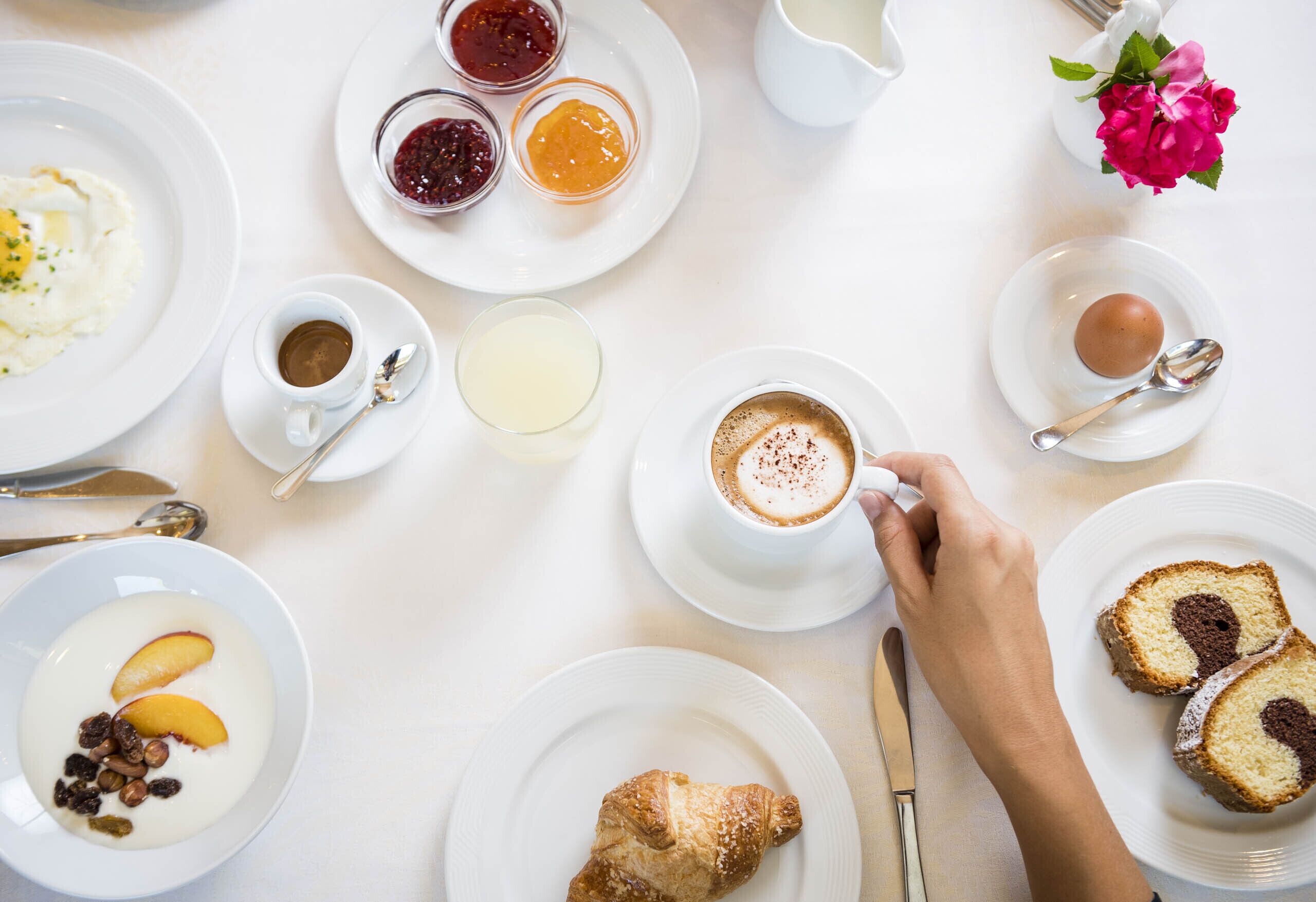 Desayuno con platos de comida, una taza de café y un jarrón de flores.