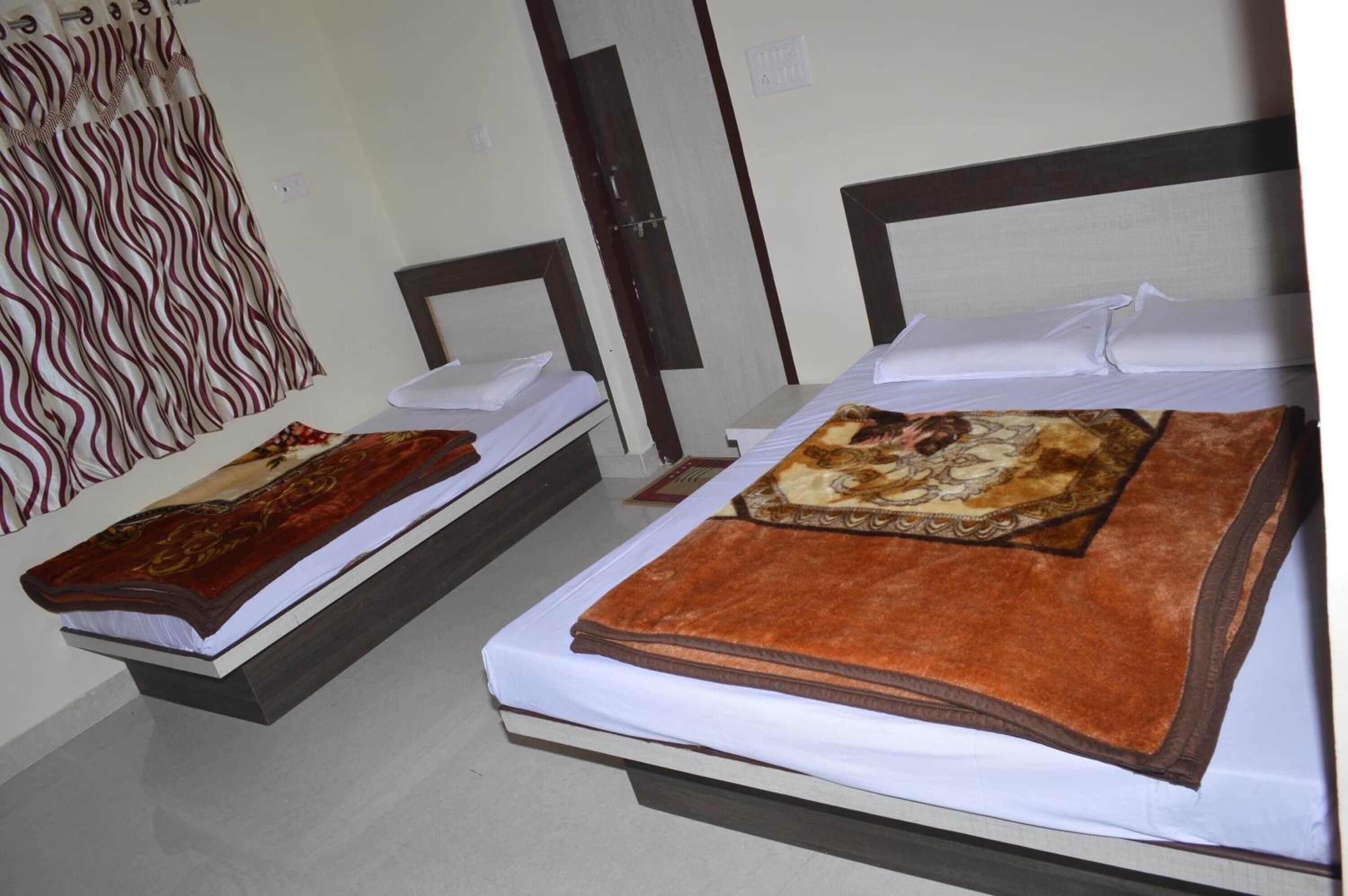 Two single beds with headboards, a patterned curtain, and a carpeted floor.