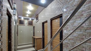 Ein moderner Hotelkorridor mit gefliesten Wänden, einem zentralen Holzbüro für die Rezeption und einer Treppe mit Metallgeländern.