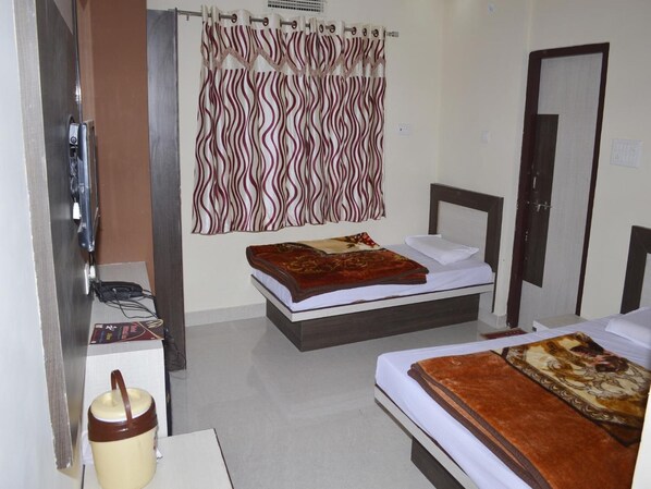 A hotel room with two beds, a small desk, a telephone, and a curtain with a wavy pattern.