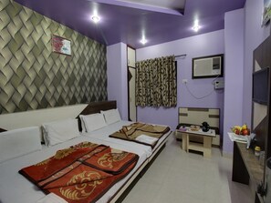 A hotel room with a bed, bedside table, and a small desk with a chair. - Hotel Mittal Inn (Ajmer)