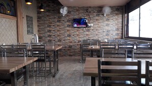 Ein Restaurant mit Backsteinwänden, Holztischen und -stühlen.