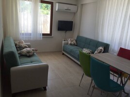 Una sala de estar con un sofá, un televisor y una mesa de comedor con sillas.