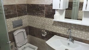 A bathroom with a toilet, bidet, sink, and a mirror above the sink.
