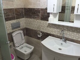 Un baño con inodoro, bidé, lavabo y un espejo sobre el lavabo.