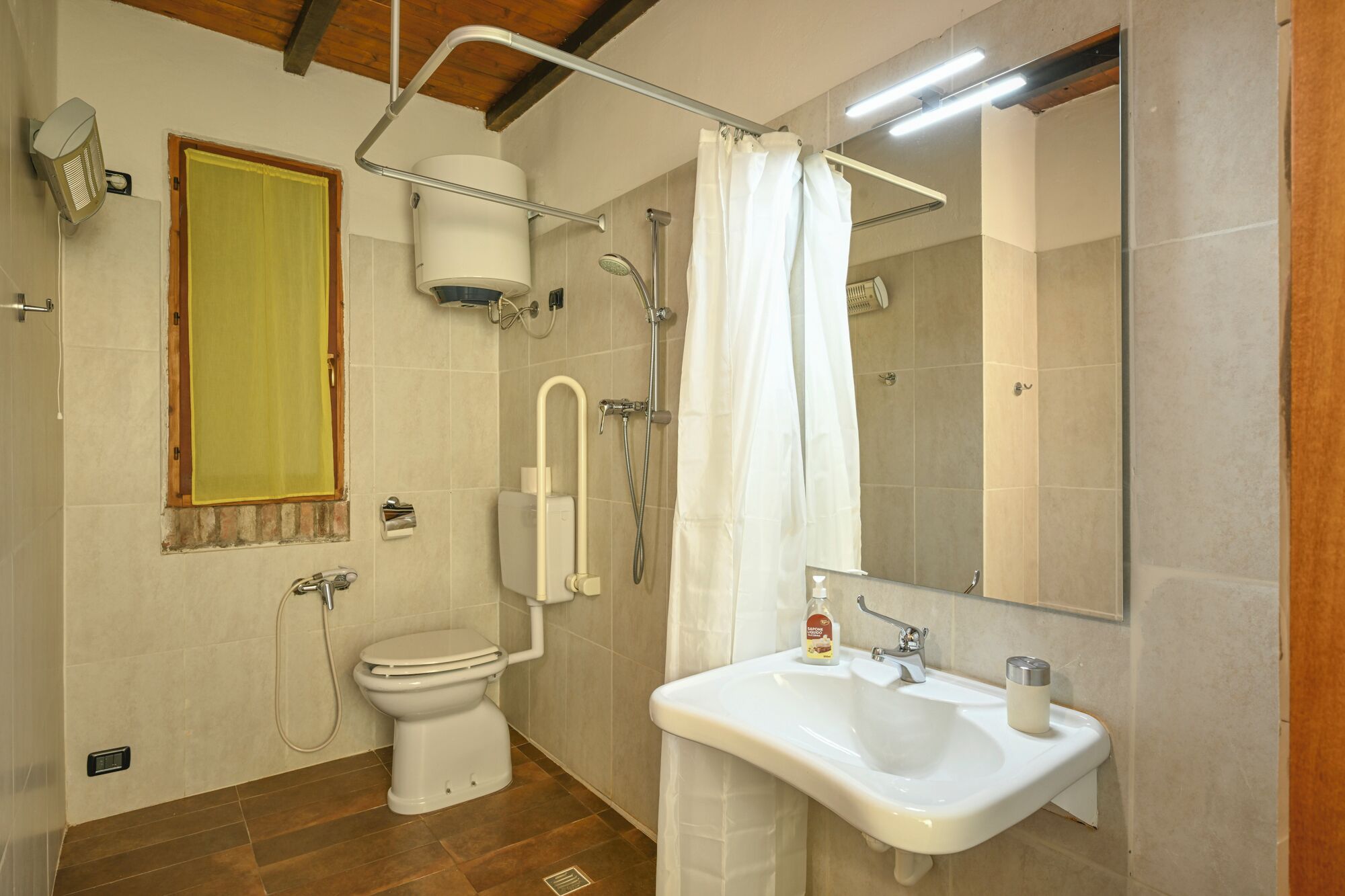 A bathroom with a toilet, shower, sink, and a mirror.