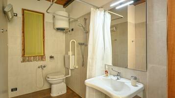 A bathroom with a toilet, shower, sink, and a mirror.
