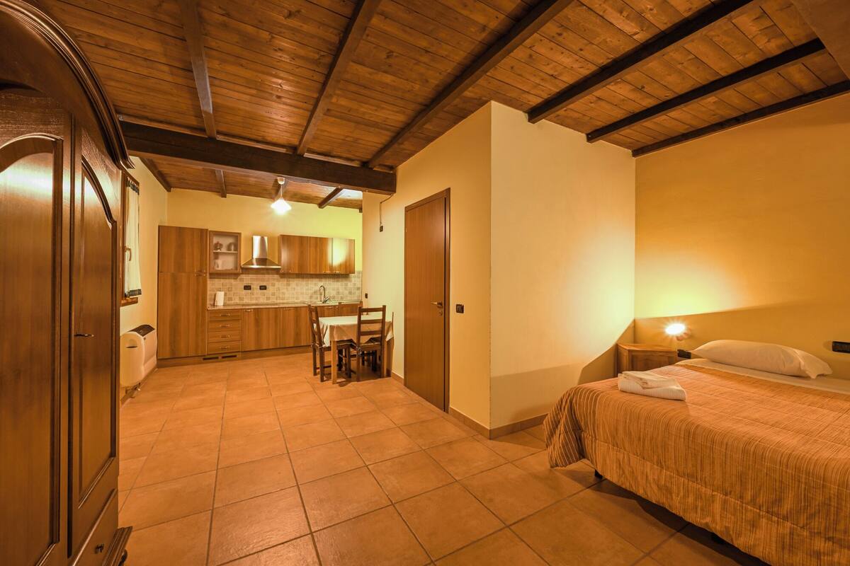 A compact room with a bed, a small kitchenette, and a dining area.