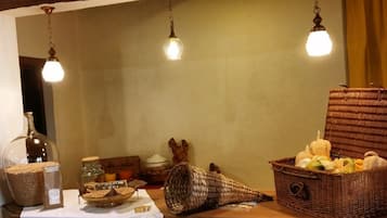 A rustic interior with a wooden table displaying various items like a glass jar, a woven basket, and a wicker basket filled with pumpkins.