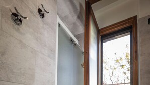 A modern bathroom with a glass shower enclosure, a wooden-framed window, and a stone-tiled wall. - Agriturismo di Sordiglio (Casina)