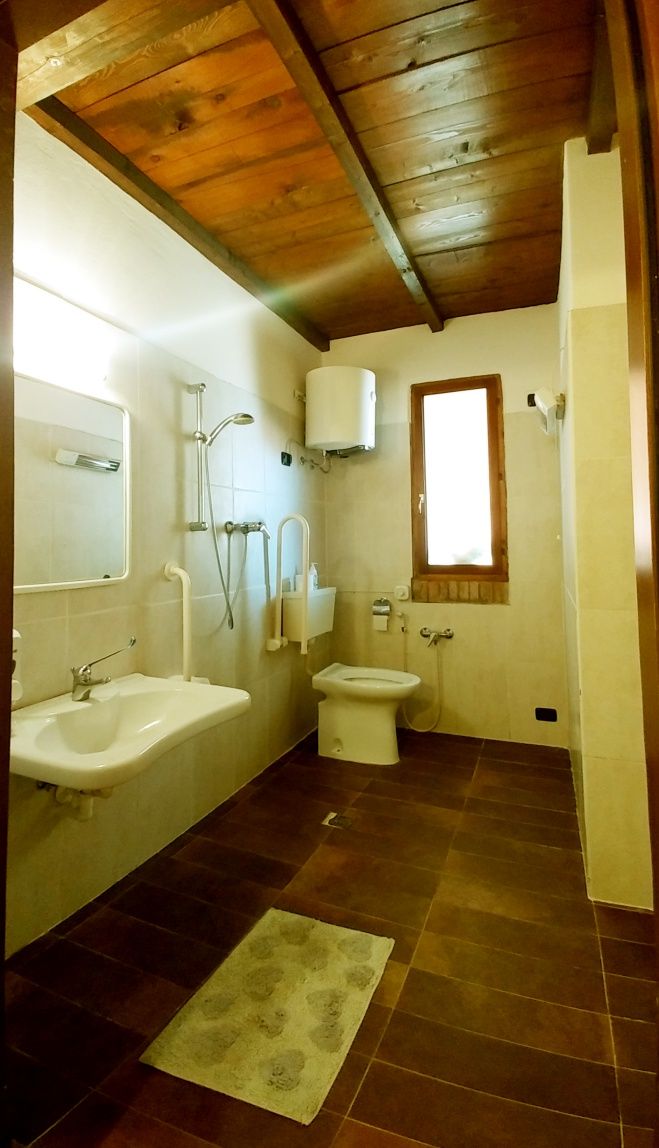 A bathroom with a wooden ceiling, a sink, a toilet, and a shower.