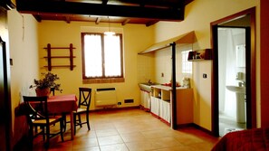 Una cocina compacta con comedor, un radiador, una ventana con cortinas y un lavamanos.