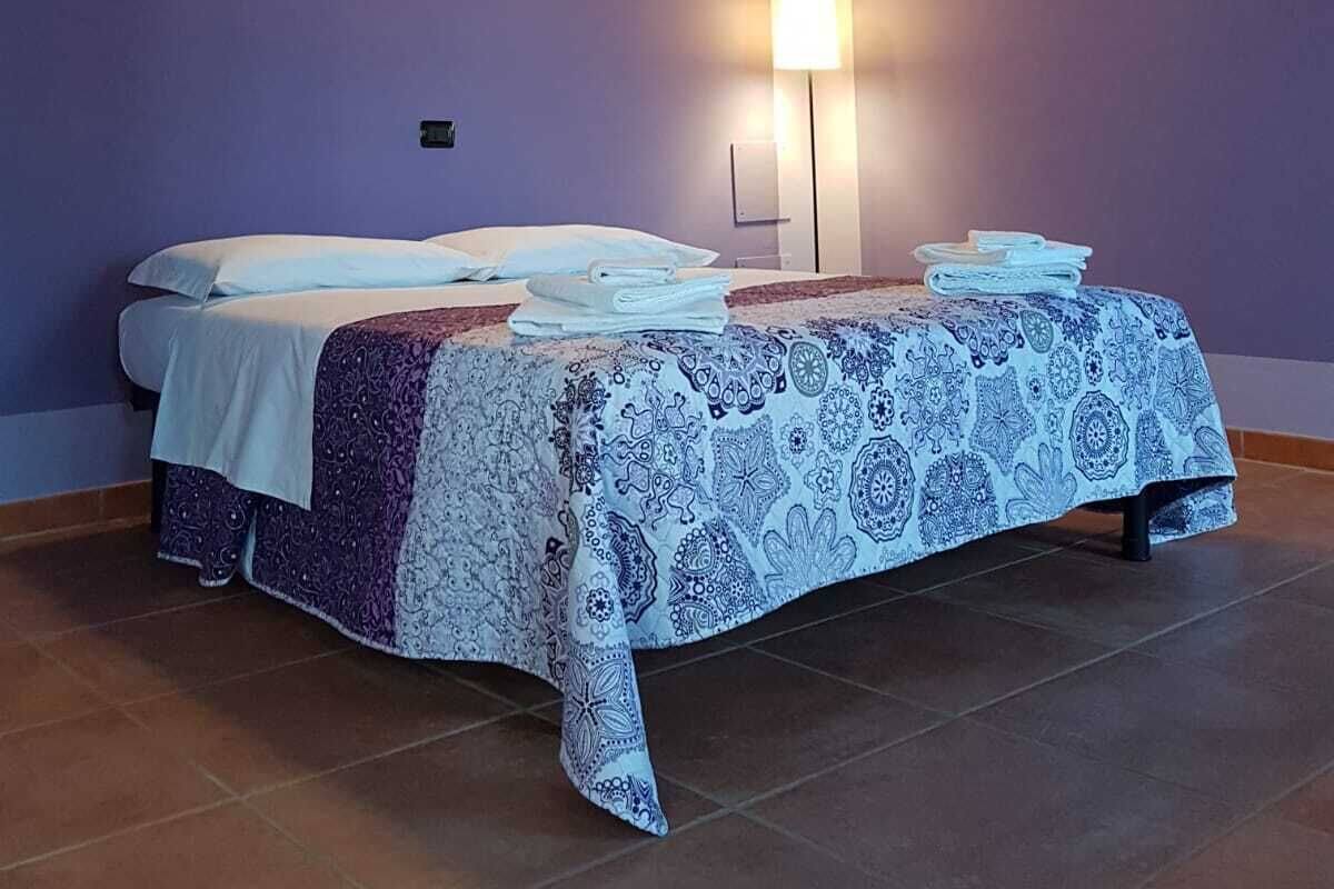 A room with a bed, a bedside table, and a wall-mounted light fixture.