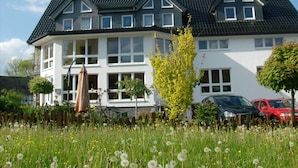 A two-story house with a dark roof, white walls, and multiple windows. - Pension & Ferienwohnung Schweinsberg (Medebach)