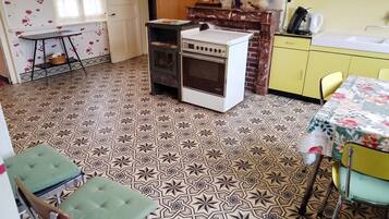 A kitchen with patterned floor tiles, a stove, a sink, and yellow cabinets.