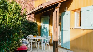 A patio with a table and chairs, a barbecue grill, and a door with a window. - Charming 4-Room Villa with Terrace & Garage - Sleeps 5, Narbonne-Plage (Narbonne-Narbonne Plage-Narbonne Plage)