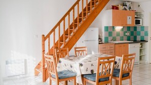 A dining area with a wooden staircase, a kitchen with a checkered backsplash, and a refrigerator. - Charming 4-Room Villa with Terrace & Garage - Sleeps 5, Narbonne-Plage (Narbonne-Narbonne Plage-Narbonne Plage)
