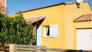 A yellow building with a tiled roof, a satellite dish, and a wooden gate. - Charming 4-Room Villa with Terrace & Garage - Sleeps 5, Narbonne-Plage (Narbonne-Narbonne Plage-Narbonne Plage)