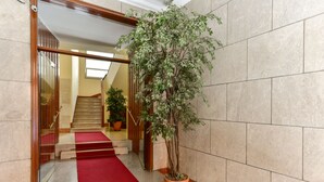 A hotel lobby with a red carpet, a staircase, and a potted plant. - Domus Bella Roma (Rome)