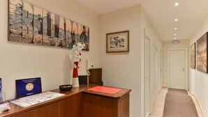 A reception desk with a map, a framed picture, and a vase with flowers. - Domus Bella Roma (Rome)