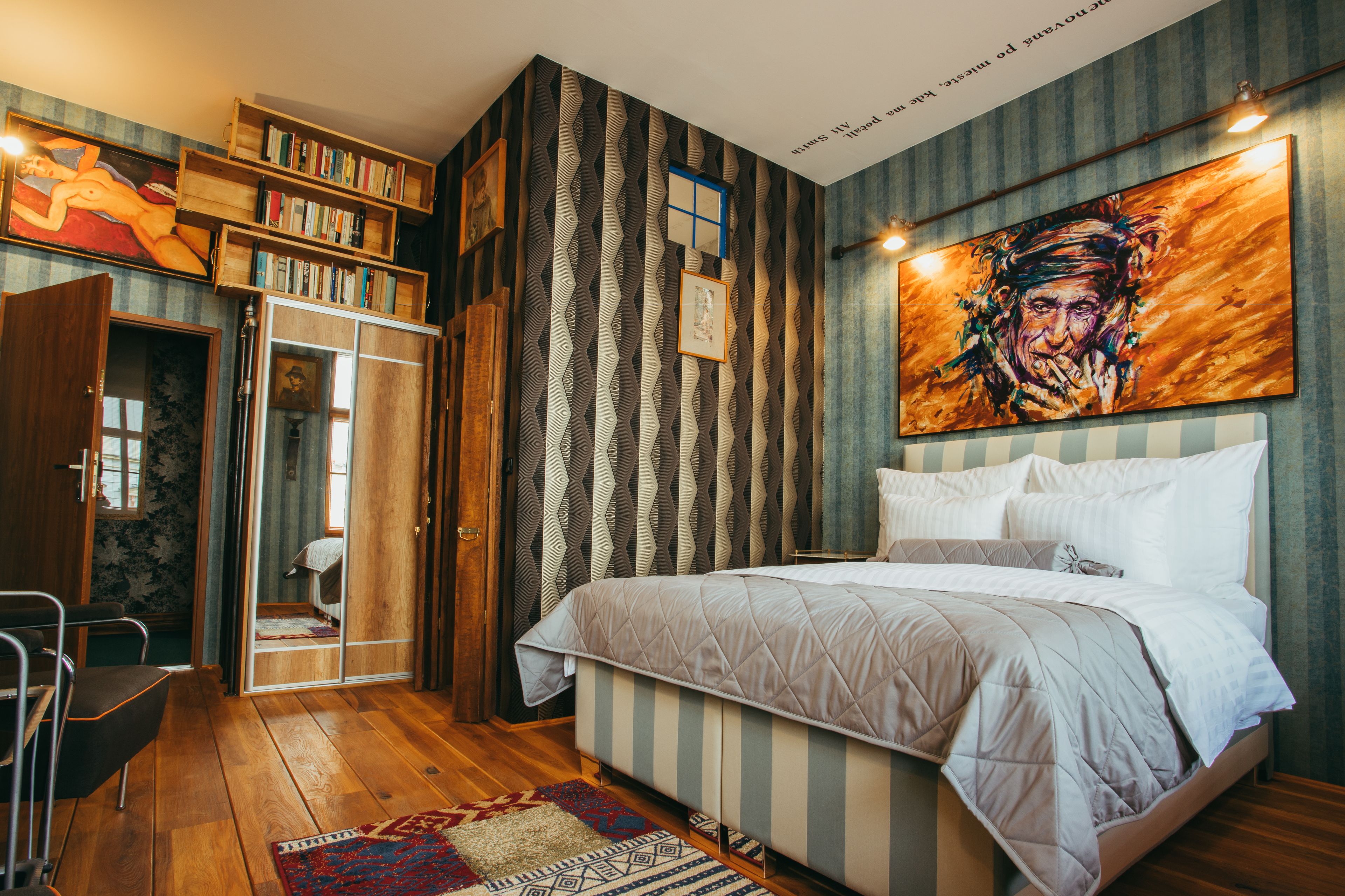 Un dormitorio con cama, estantería, armario y un cuadro en la pared.
