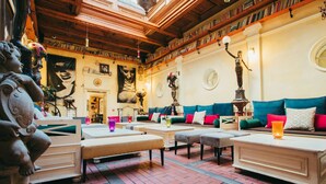 A cozy lounge area with sofas and tables, a brick floor, and a wooden ceiling.