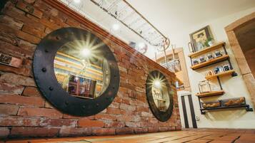A brick wall with two large circular mirrors and a metal ceiling with hanging lights.