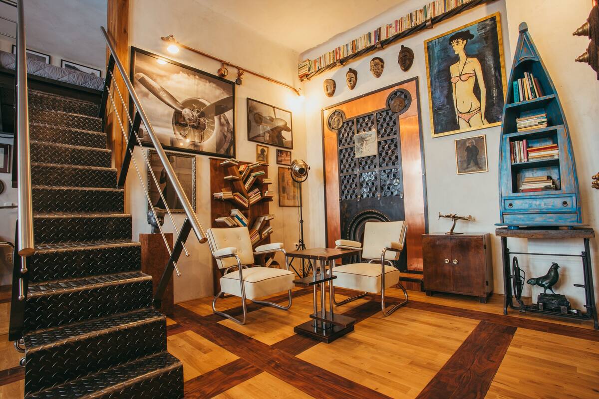 A room with a staircase, bookshelves, and a fireplace.