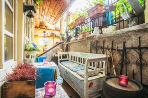 A cozy outdoor seating area with a wooden bench, a table with a candle, and various potted plants. - Divná Pani Luxury Gallery Rooms (Banska Stiavnica)