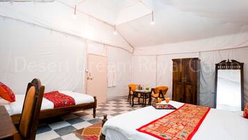 Una habitación con carpa, dos camas, un armario de madera, una mesa con sillas y suelo a cuadros.