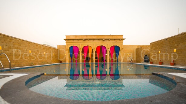 Una piscina con vistas claras a la arquitectura circundante, incluyendo un edificio con arcos y un muro de ladrillo.