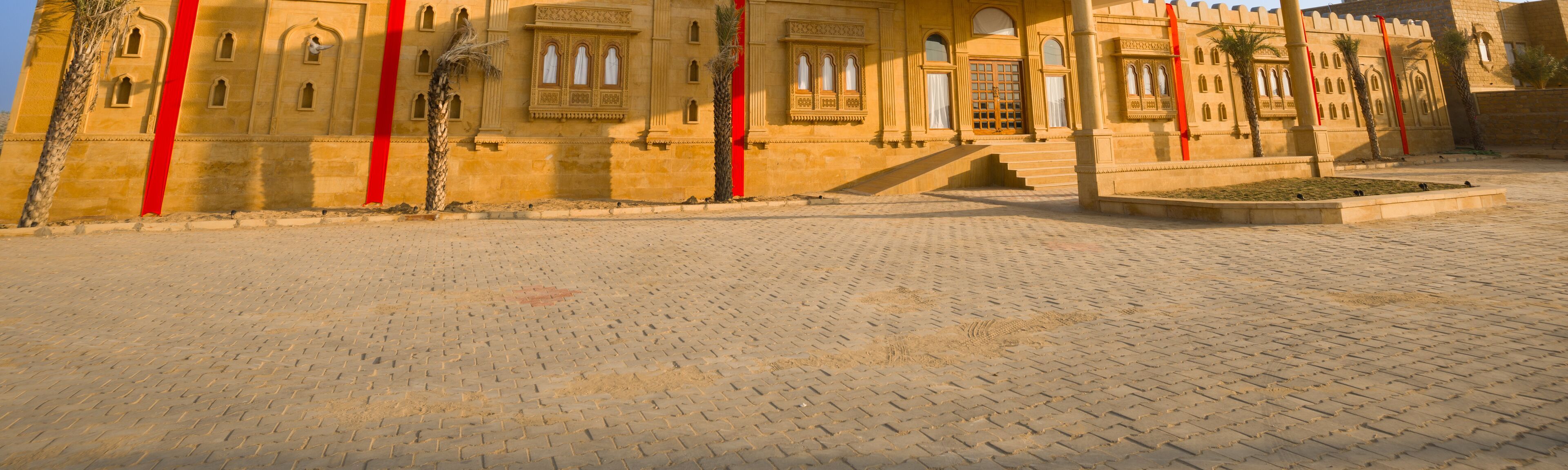 A courtyard with a paved walkway and a building with arched windows and decorative elements.