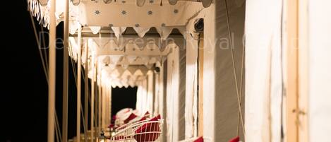 A row of white chairs with red cushions, arranged in a tent-like structure with a patterned ceiling.