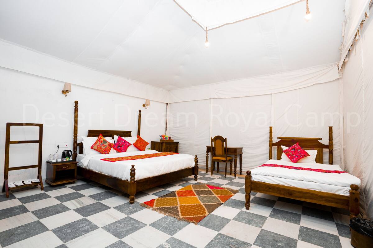 Een kamer met twee houten bedden, een tafeltje, een stoel en een geruite vloer.