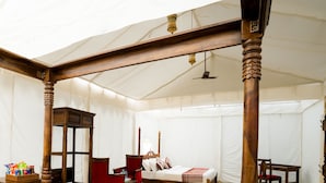 Una habitación con carpa, una cama con dosel, una mesa de madera y una silla.