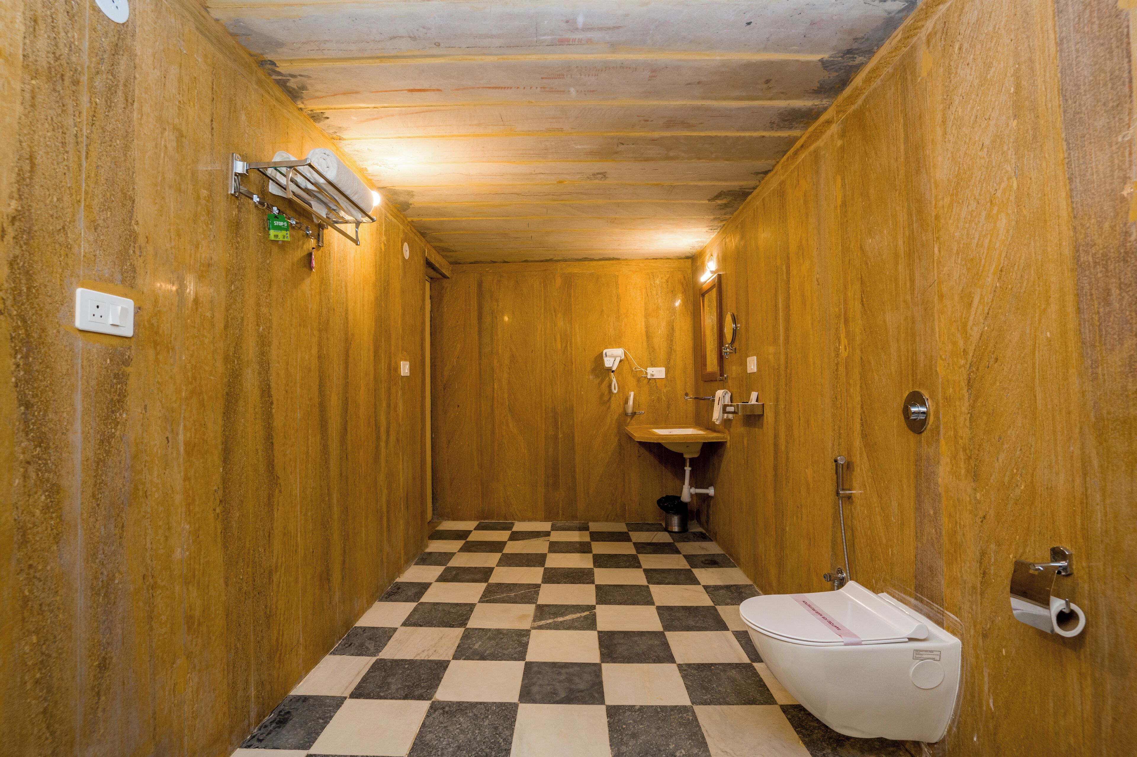 Ein kleines, schmales Badezimmer mit einem Schachbrettmuster-Boden, Holzwänden, einem Waschbecken und einer Toilette.