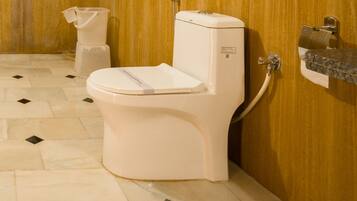 Une salle de bain équipée de toilettes, d’un distributeur d’essuie-tout et d’un sèche-mains.