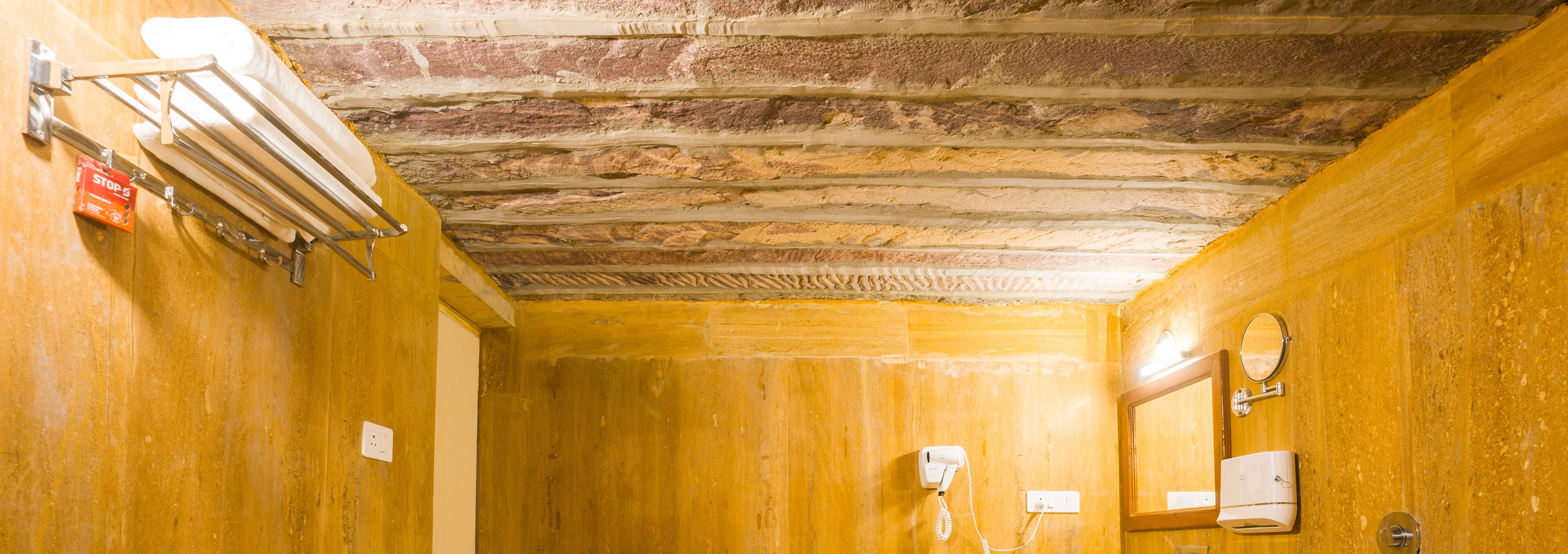 A bathroom with wooden walls, a towel rack, a hairdryer, a mirror, and a wall-mounted phone.