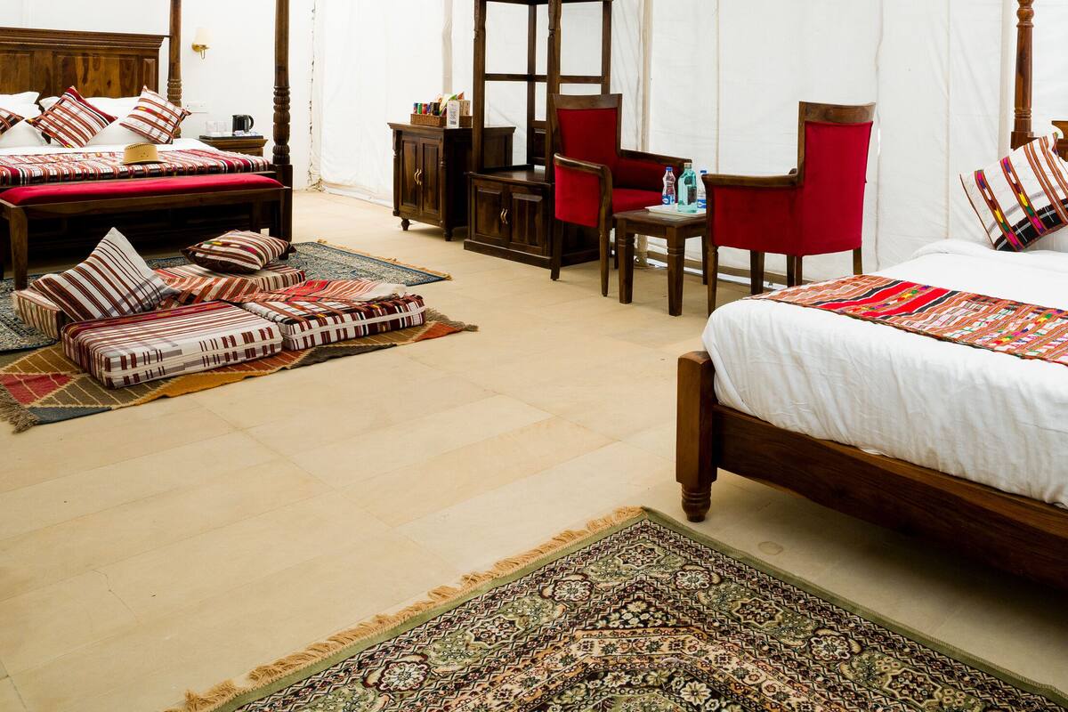 Een ruime slaapkamer met een groot bed, een houten baldakijn en een rode stoel.