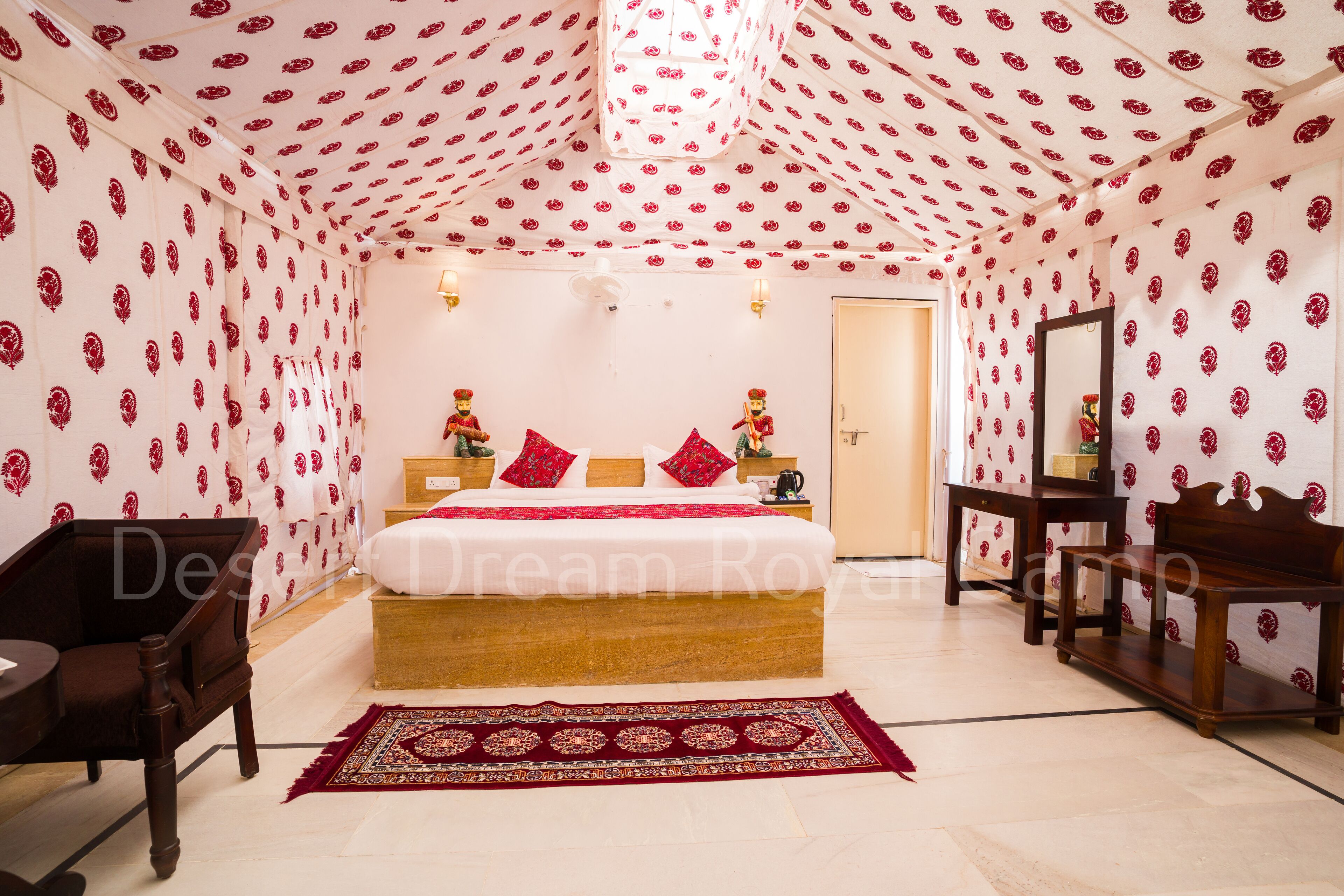 A bedroom with a bed, a nightstand, a wooden chair, a wooden bench, and a patterned rug.