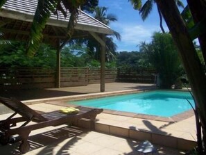 Una piscina al aire libre, sillones reclinables de piscina