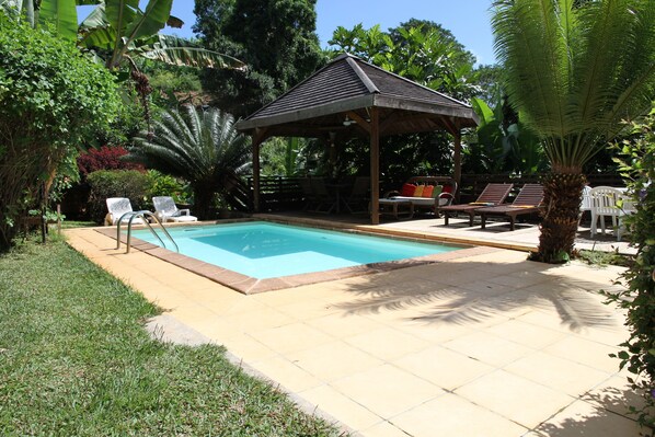 Relax by the clear pool surrounded by lush greenery and comfortable lounge chairs.