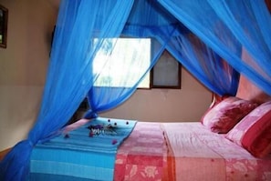Cozy retreat with a bed under a canopy, adorned with a vibrant bedspread and a framed picture above.