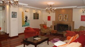 A living room with a fireplace, red sofas, a coffee table, and artwork on the walls. - Stunning Mansion (Nairobi)