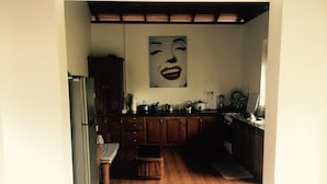 Una cocina con armarios de madera, un refrigerador y un cuadro grande en la pared.