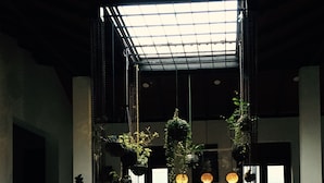 Un vestíbulo moderno con un sofá negro, plantas colgantes e iluminación colgante.